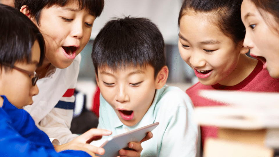 Children learning English with Little Bridge on a tablet, looking excited