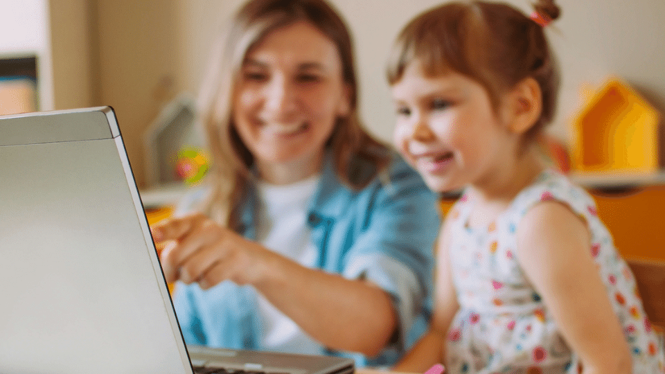 A parent helps their child learn English at home with Little Bridge