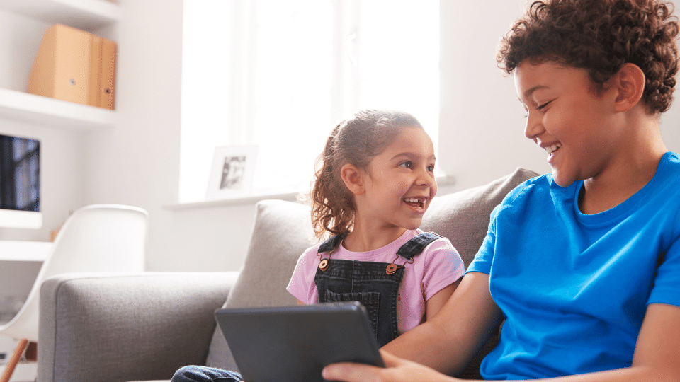 Two kids learning English with Little Bridge on a tablet at home